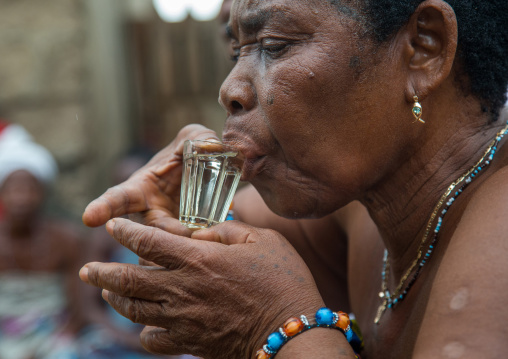 Benin, West Africa, Bopa, woman drinking alcohol during a voodoo ceremony