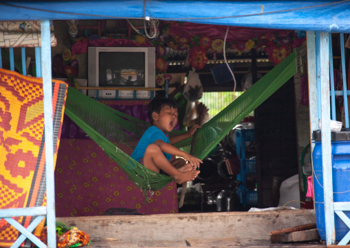 Cambodian boy on a hammock in the floating village on Tonle Sap lake, Siem Reap Province, Chong Kneas, Cambodia