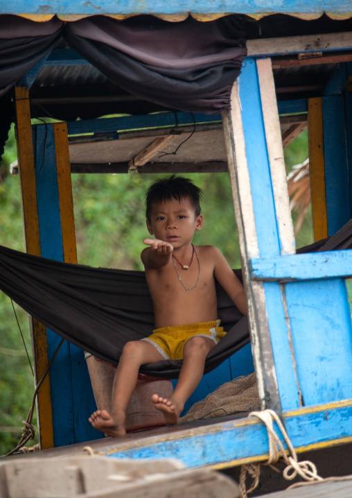 Cambodian boy on a hammock asking for money in the floating village on Tonle Sap lake, Siem Reap Province, Chong Kneas, Cambodia