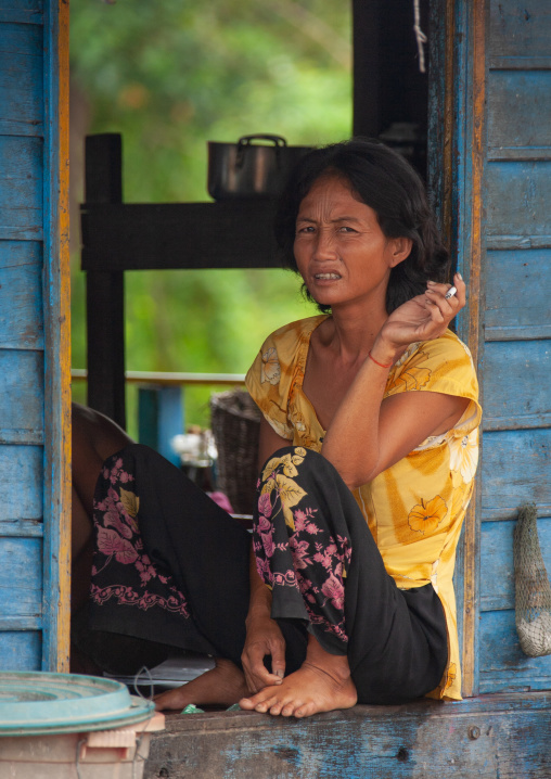 Cambodian woman sit at the door of her house in the floating village on Tonle Sap lake, Siem Reap Province, Chong Kneas, Cambodia