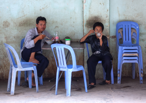 Father ans son eating in an outdoors restaurant, Phnom Penh province, Phnom Penh, Cambodia