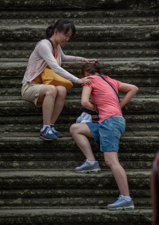Asian tourists women climbing steps at Angkor wat, Siem Reap Province, Angkor, Cambodia