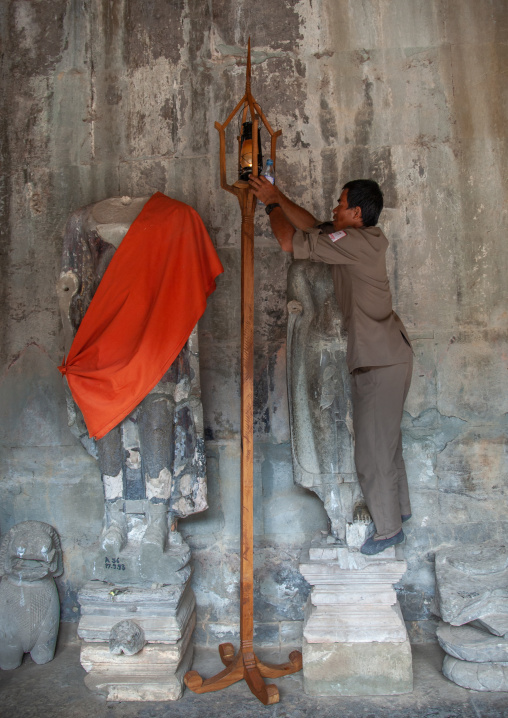 Cambodian guard putting a lamp in a temple, Siem Reap Province, Angkor, Cambodia