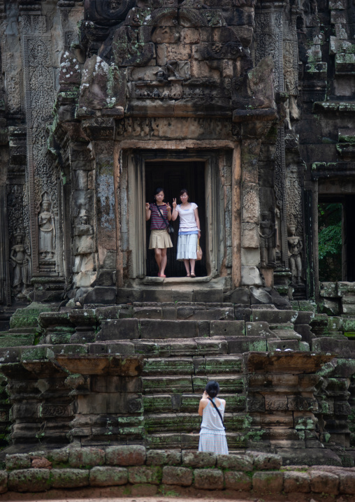 Asian tourists taking pictures in old ruins of a temple in Angkor wat, Siem Reap Province, Angkor, Cambodia