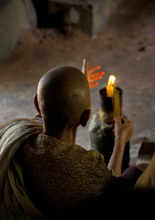 Female monk with a candle praying inside a tempe in Angkor wat, Siem Reap Province, Angkor, Cambodia