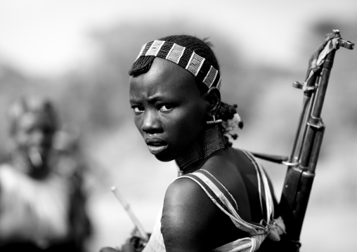 Hamer Tribe Woman Walking With  Rifle During Bull Leaping Ceremony And Giving A Disdainful Look, Omo Valley, Ethiopia