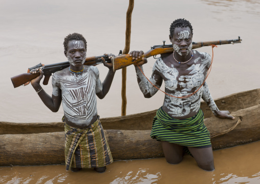 Young Karo Men With White Painted Faces And Chests Holding Kalashnikov Rifle In The Water Of The River Near Pirogue Omo Valley Ethiopia