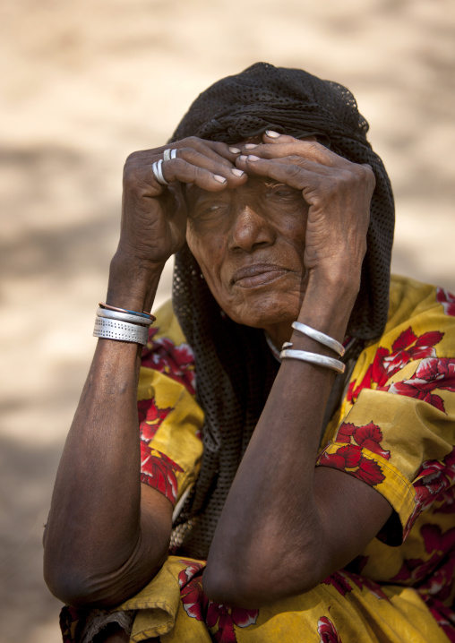 Portrait Of An Old Karrayyu Tribe Woman Squatting And Protecting Her Eyes From The Sun, Metahara, Ethiopia