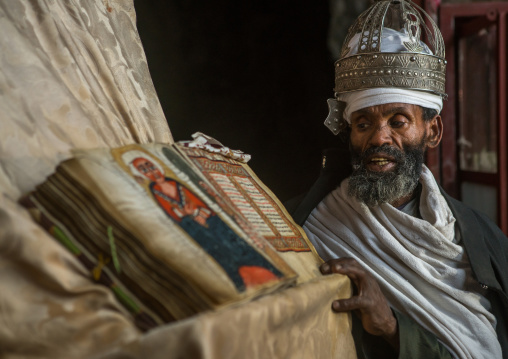 Ethiopian orthodox priest with an old bible in nakuto lab rock church, Amhara region, Lalibela, Ethiopia