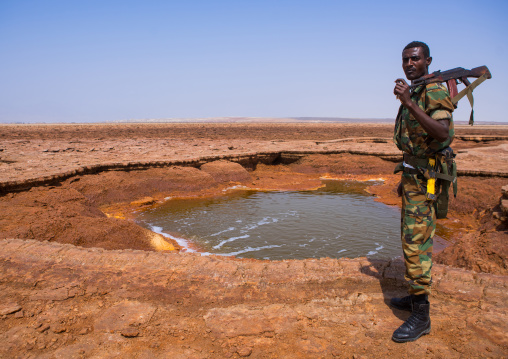 An ethiopian soldier in front of an acid lake in the danakil depression, Afar region, Dallol, Ethiopia