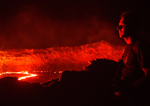 Tourist in front of the living lava lake in the crater of erta ale volcano, Afar region, Erta ale, Ethiopia