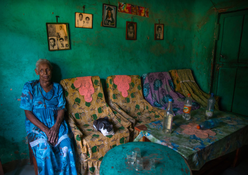 Old woman inside her house decorated with old pictures of her relatives, Omo valley, Jinka, Ethiopia