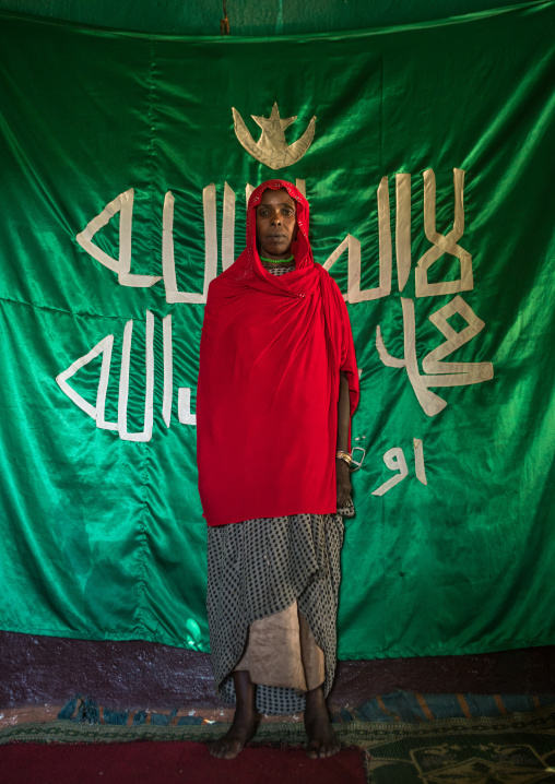 Sufi woman worshipper in front of islamic green flag, Harari region, Harar, Ethiopia