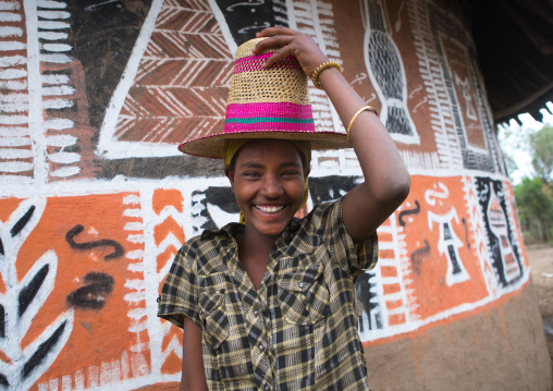 Ethiopia, Kembata, Alaba Kuito, ethiopian woman with a hat standing in front of her traditional painted house