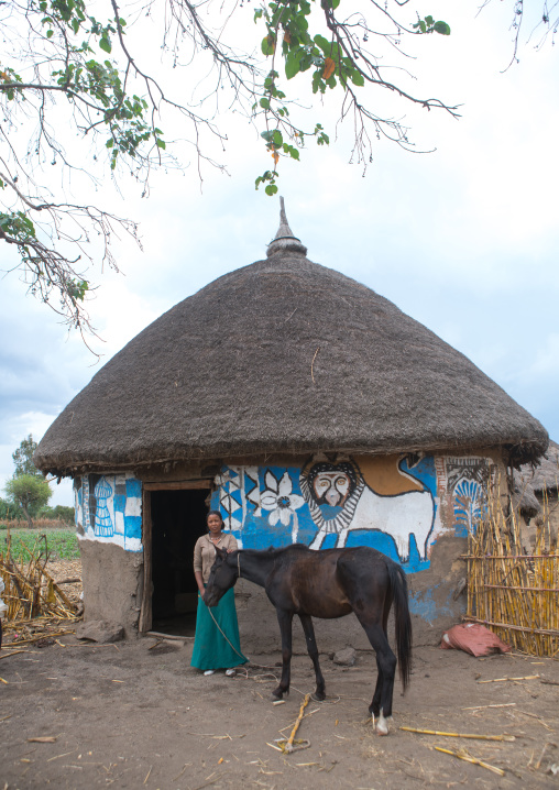 Ethiopia, Kembata, Alaba Kuito, ethiopian woman standing in front of her traditional painted house with a horse