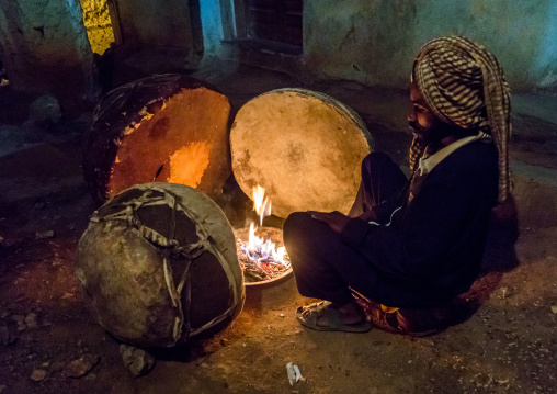 Harari man heating the drums before a ceremony in sufi community, Harari Region, Harar, Ethiopia