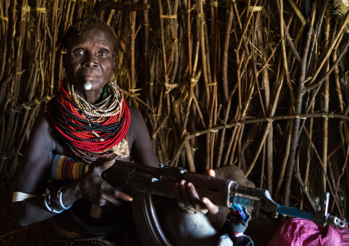 Nyangatom tribe woman holding a kalashnikov in her hut, Omo valley, Kangate, Ethiopia