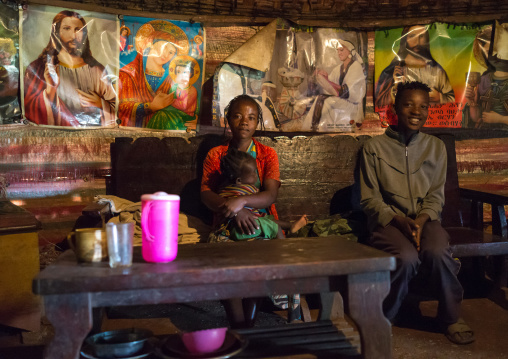 Family sit in a house decorated with christian posters, Gamo Gofa Zone, Ganta, Ethiopia