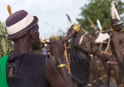 Man blowing a horn during the Bodi tribe fat men Kael ceremony, Omo valley, Hana Mursi, Ethiopia