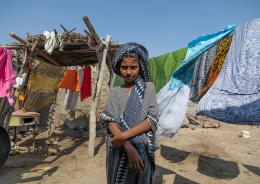 Ethiopian girl in the middle of clothes drying outside, Afar Region, Assayta, Ethiopia