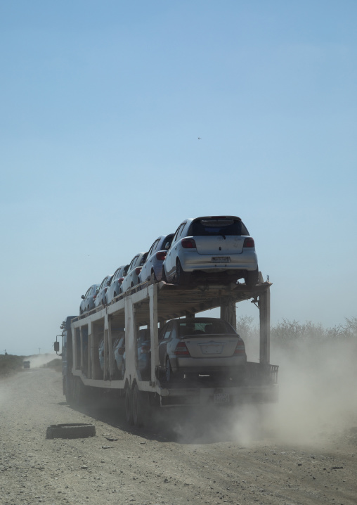 Truck carrying new cars coming from djibouti port on a dusty road, Oromia, Awash, Ethiopia