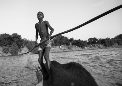 Young Boy Pushing A Boat On The Omo River, Omorate, Omo Valley, Ethiopia