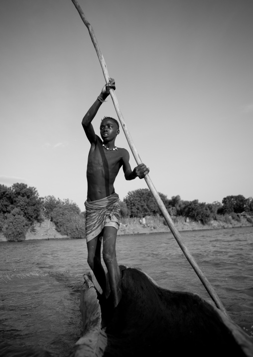 Young Boy Pushing A Boat On The Omo River, Omorate, Omo Valley, Ethiopia