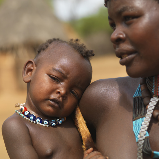 Tsemay mother and her baby in arms both with beaded necklaces, Omo valley, Ethiopia