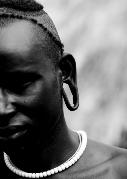 Black And White Partial Portrait Of A Surma Tribe Warrior With Enlarged Ear, Omo Valley, Ethiopia