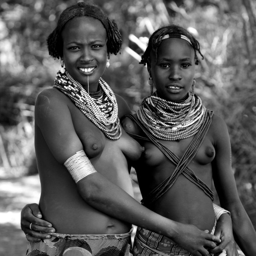 Black And White Portrait Of Two Young Dassanech Tribe Girls With Traditional Jewels And Hairstyle, Omorate, Omo Valley, Ethiopia