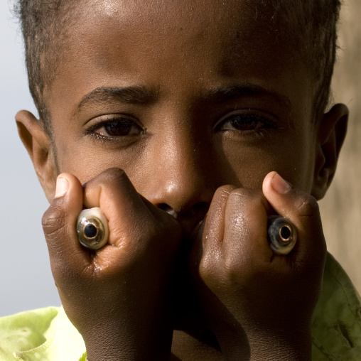 Portrait of a kid with the fresh fish eyes he just pulled out as his job on zway lake market, Ethiopia