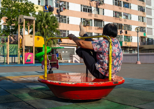 Chinese woman maknig gymnastic on a playground, Kowloon, Hong Kong, China