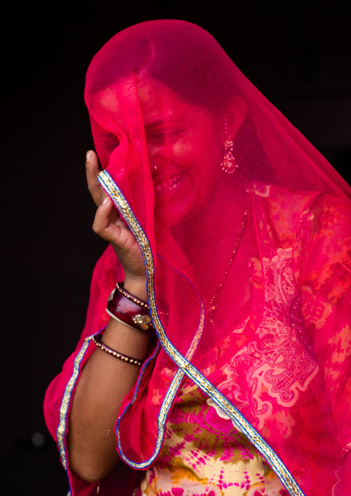 Portrait of a rajasthani woman hidding her face under a red sari, Rajasthan, Jaisalmer, India