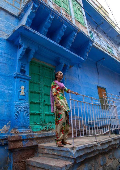 Indian girl standing in front of an old blue house of a brahmin, Rajasthan, Jodhpur, India