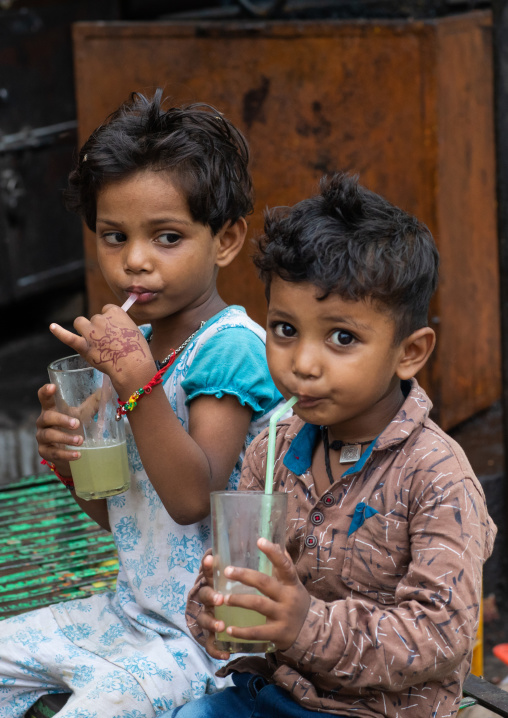 Indian children drinking lemonade in the street with plastic straws, Rajasthan, Bundi, India