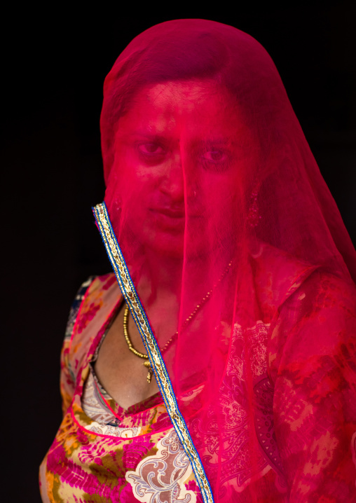 Portrait of a rajasthani woman hidding her face under a red sari, Rajasthan, Jaisalmer, India