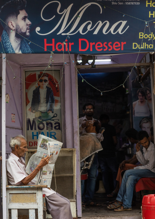 Hairdresser cutting man's hair on the streets, Rajasthan, Bundi, India