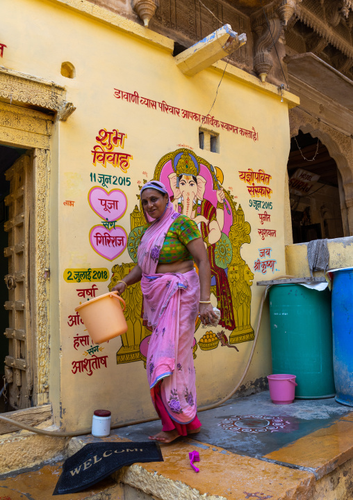 Portrait of a rajasthani woman in traditional sari washing her home, Rajasthan, Jaisalmer, India