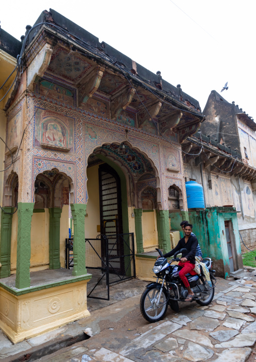 Indian man on a motorbike in front of an old historic haveli, Rajasthan, Nawalgarh, India