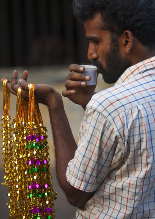 Rear View Of Seller Of Necklaces Drinking In A Plastic Cup, Chennai, India