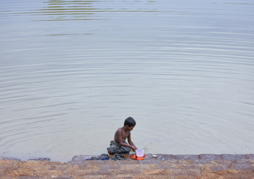 Young Shirtless Boy Doing His Laundry On The Banks Of A River, Kanadukathan Chettinad, India