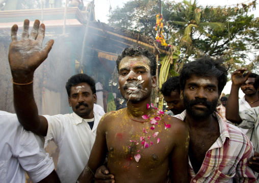 Man With Peaks Symbolizing Hindu Gods' Weapons On His Tongue Covered With Ashes And Petals Supported By Friends During Fire Walking Ritual, Madurai, South India