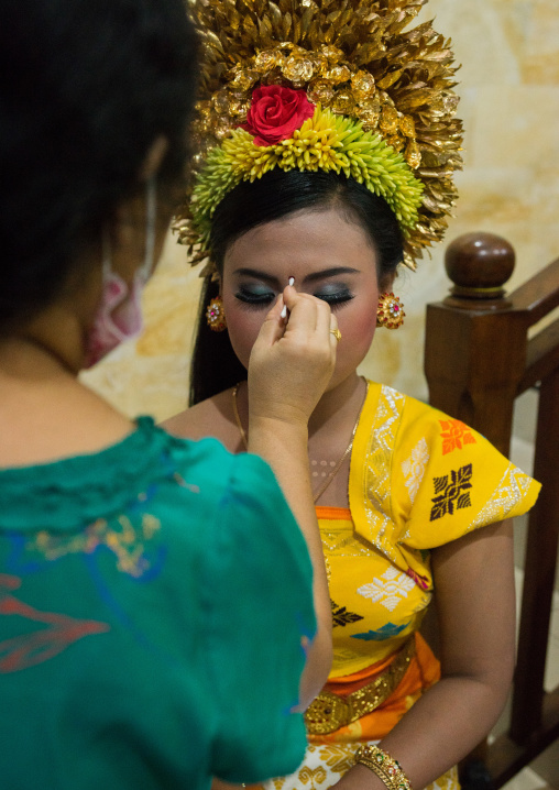 A Woman Applying Makeup To A Teenager Girl In Traditional  Costume Before A Tooth Filing Ceremony