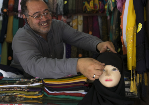 Man putting a veil on a mannequin in the bazaar, Fars province, Shiraz, Iran