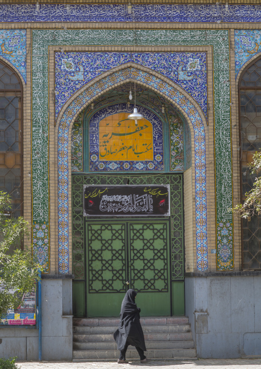Woman passing in front of a mosque, Isfahan province, Kashan, Iran