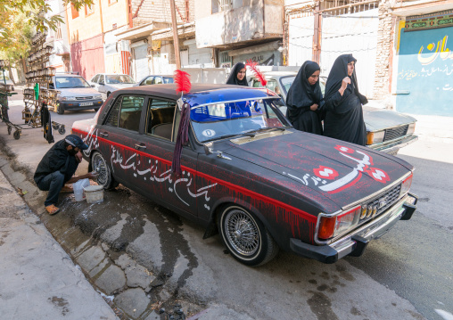 A shiite iramian man washes his car decorated for Ashura celebrations to commemorate the martyrdom anniversary of Hussein, Lorestan Province, Khorramabad, Iran