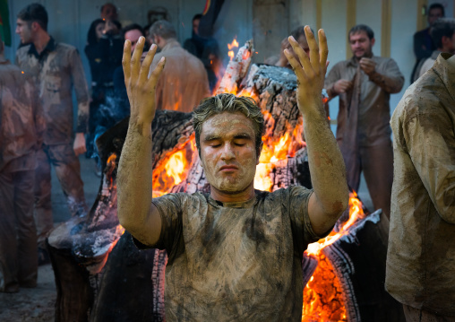 Iranian shiite muslim men pray and gather around a bonfire after rubbing mud on their bodies during the Kharrah Mali ritual to mark the Ashura day, Lorestan Province, Khorramabad, Iran