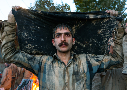 Iranian shiite muslim man drying his clothes after rubbing mud on his body during the Kharrah Mali ritual to mark the Ashura ceremony, Lorestan Province, Khorramabad, Iran