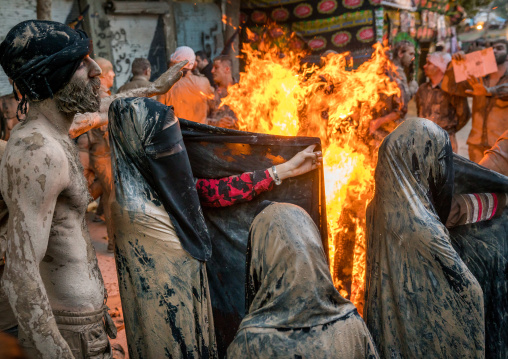 Iranian shiite muslim women gather around a bonfire after rubbing mud on their chadors during the Kharrah Mali ritual to mark the Ashura day, Lorestan Province, Khorramabad, Iran