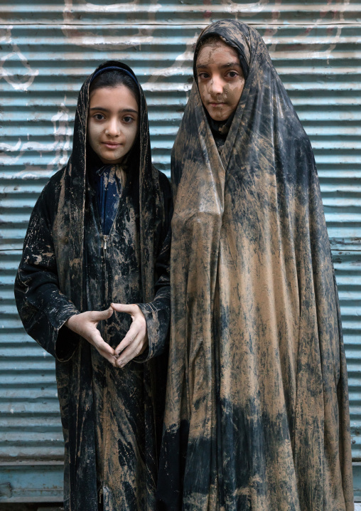 Portrait of iranian shiite muslim girls with mud stains on their chadors during the Ashura day, Lorestan Province, Khorramabad, Iran